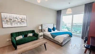 a bedroom with a bed and a green couch at Rare Holiday Homes - Lake View - Near Me'aisem City Centre - The Crescent Tower A - Dubai Production City - R910 in Dubai