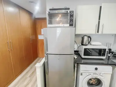 a kitchen with a microwave on top of a refrigerator at Rare Holiday Homes - Near The Lake - Lago Vista B - Dubai Production City - IMPZ - R2112 in Dubai