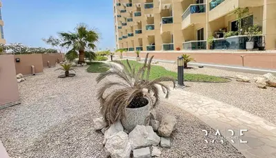 a plant in a pot on a sidewalk in front of a building at Rare Holiday Homes - Near The Lake - Lago Vista B - Dubai Production City - IMPZ - R2112 in Dubai