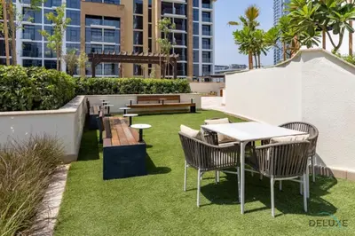 a patio with a table and chairs and grass at Comfortable Studio in Azizi Riviera 24, Al Merkadh by Deluxe Holiday Homes in Dubai