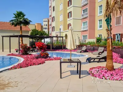 a hotel courtyard with a pool and a umbrella at Rare Holiday Homes - Mediterranean Cluster - Near Ibn Battuta Mall - Discovery Garden - Building# Med 49 - R514 in Dubai