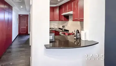 a kitchen with red cabinets and a counter top at Rare Holiday Homes - Mediterranean Cluster - Near Ibn Battuta Mall - Discovery Garden - Building# Med 49 - R411 in Dubai