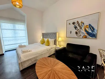 a bedroom with a bed and a chair and a table at Rare Holiday Homes - Mediterranean Cluster - Near Ibn Battuta Mall - Discovery Garden - Building# Med 49 - R505 in Dubai