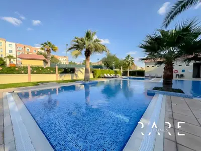a swimming pool in a resort with palm trees at Rare Holiday Homes - Mediterranean Cluster - Near Ibn Battuta Mall - Discovery Garden - Building# Med 49 - R505 in Dubai