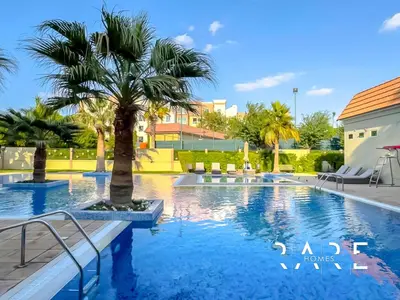a swimming pool with a palm tree in a resort at Rare Holiday Homes - Mediterranean Cluster - Near Metro - Discovery Garden - Building# Med 103 - RG07 in Dubai
