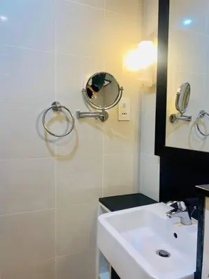 a white bathroom with a sink and a mirror at Downtown Studio - Cour Jardin in Dubai