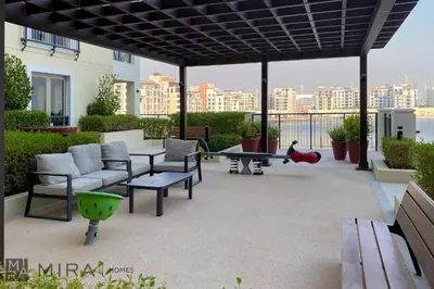a patio with a couch and a table and chairs at Mira Holiday Homes - Luxury 2 bedroom in Le Pont in Dubai