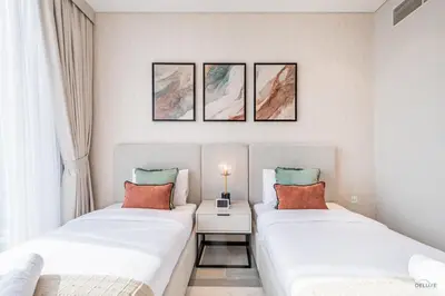 two beds in a room with a table at Waterfront Living 2BR Apartment in Marina Star, Dubai Marina by Deluxe Holiday Homes in Dubai