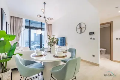 a dining room with a white table and blue chairs at Luxurious 2BR Apartment in Azizi Riviera 18, Al Merkadh by Deluxe Holiday Homes in Dubai