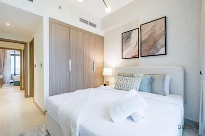 a white bedroom with a large white bed with pillows at Luxurious 2BR Apartment in Azizi Riviera 18, Al Merkadh by Deluxe Holiday Homes in Dubai