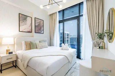 a bedroom with a white bed and a large window at Luxurious 2BR Apartment in Azizi Riviera 18, Al Merkadh by Deluxe Holiday Homes in Dubai
