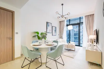 a dining room with a white table and chairs at Luxurious 2BR Apartment in Azizi Riviera 18, Al Merkadh by Deluxe Holiday Homes in Dubai