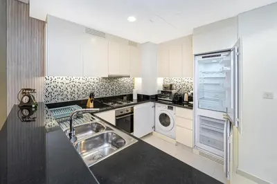 a white kitchen with a sink and a dishwasher at 3 King Beds - 7mins to Dubai Mall - High Floor Sun Set and Sea View in Dubai