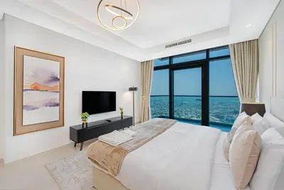 a white bedroom with a large bed and a large window at 3 King Beds - 7mins to Dubai Mall - High Floor Sun Set and Sea View in Dubai