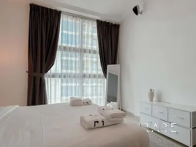 a white bedroom with a large window with towels on a bed at Rare Holiday Homes - Near Madame Tussauds - DEC Tower 1 - Dubai Marina - R2008 in Dubai