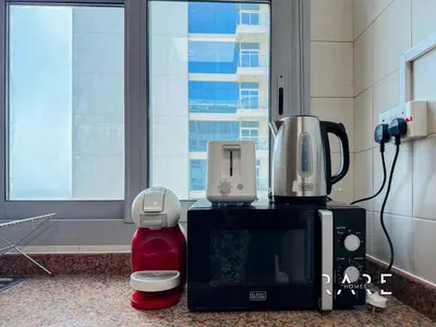a kitchen with a coffee maker and a microwave at Rare Holiday Homes - Near Madame Tussauds - DEC Tower 1 - Dubai Marina - R2008 in Dubai