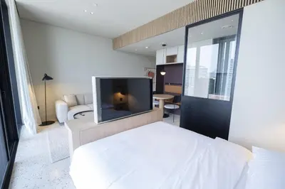 a bedroom with a white bed with a flat screen tv at Modern Studio at Upside Living, Business Bay with Burj Khalifa View in Dubai