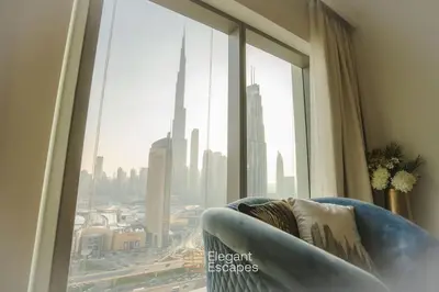 a blue chair in a room with a large window at Stylish 2 BR Apt, Amazing Fountains and Burj Views in Dubai