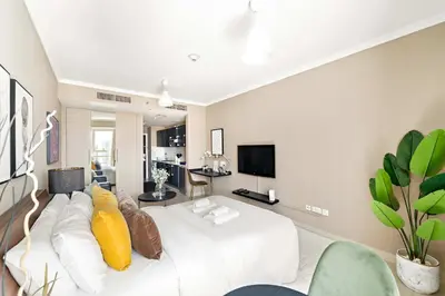 a bedroom with a white bed with a yellow pillow on it at Silkhaus Modern Studio near Almas in West Lake in Dubai