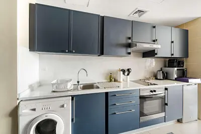 a kitchen with blue cabinets and a washing machine at Silkhaus Modern Studio near Almas in West Lake in Dubai