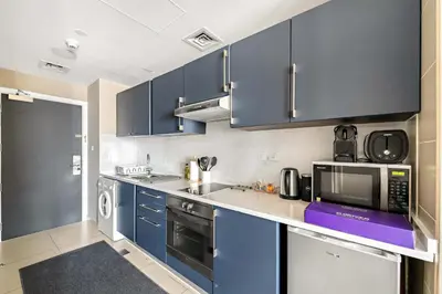 a kitchen with blue cabinets and a microwave at Silkhaus Modern Studio near Almas in West Lake in Dubai
