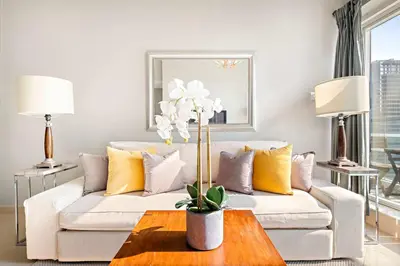 a living room with a white couch and yellow pillows at Silkhaus Modern 1BDR near Almas in East Lake in Dubai