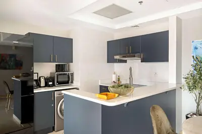 a kitchen with blue cabinets and a white counter top at Silkhaus Modern 1BDR near Almas in East Lake in Dubai