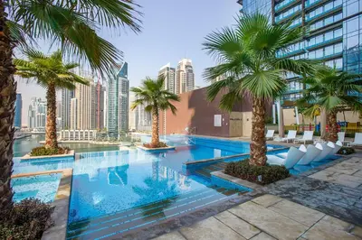 a swimming pool with palm trees in a city at Blueground Marina Gate city view sauna gym DXB-1338 in Dubai