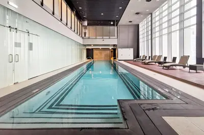 a large swimming pool in a building with chairs at Blueground DIFC indoor pool fitness center DXB-1515 in Dubai