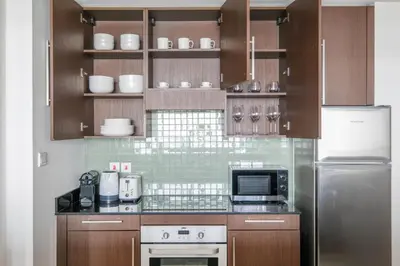 a kitchen with wooden cabinets and a microwave and a refrigerator at Blueground DIFC Burj K view pool fitness DXB-1535 in Dubai