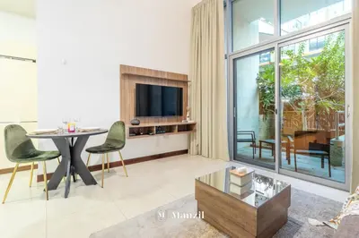 a living room with a table and a tv at Manzil - Studio in JVC w Premium Amenities near Circle Mall in Dubai