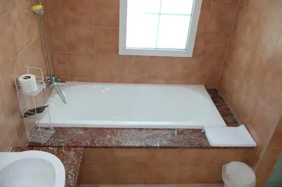 a bathroom with a tub and a toilet and a window at Fully Furnished Garden Villa 2 Bedroom in Dubai