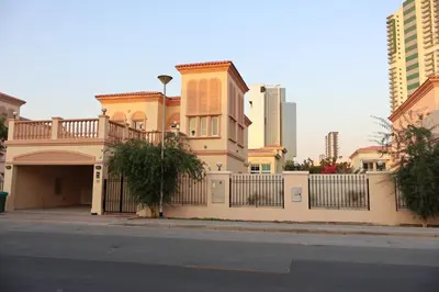 a yellow house with a gate and a fence at Fully Furnished Garden Villa 2 Bedroom in Dubai