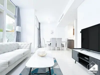 a living room with a white couch and a tv at Luxury 3-Bedroom Duplex in Damac Hills & balcony in Dubai