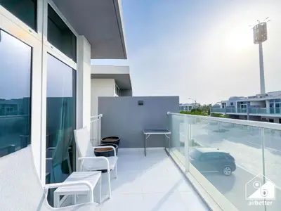 a balcony with white chairs and a car on a building at Luxury 3-Bedroom Duplex in Damac Hills & balcony in Dubai