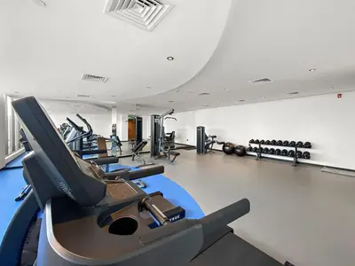 a gym with a row of treadmills and machines at Cosy 1bedroom apartment with pool gym game room in Dubai