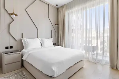a bedroom with a white bed and a large window at Cosy 1bedroom apartment with pool gym game room in Dubai