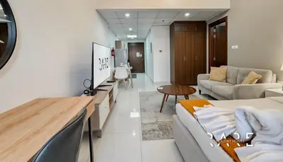 a living room with a couch and a tv at Rare Holiday Homes - Dubai Sports City - Elite Residence - R1303 in Dubai