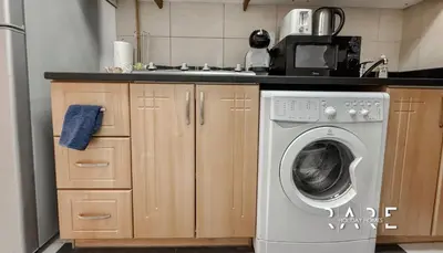 a kitchen with a washing machine and a sink at Rare Holiday Homes - Dubai Sports City - Elite Residence - R1303 in Dubai