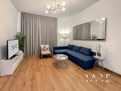 a living room with a blue couch and a tv at Rare Holiday Homes - Near Circle Mall - Lavender 1 - R309 - Jumeirah Village Circle in Dubai