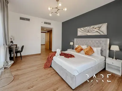 a bedroom with a large bed and a table at Rare Holiday Homes - Near Circle Mall - Lavender 1 - R309 - Jumeirah Village Circle in Dubai