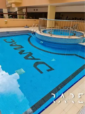 a swimming pool in a building with blue water at Rare Holiday Homes - Near Circle Mall - Lavender 1 - R309 - Jumeirah Village Circle in Dubai