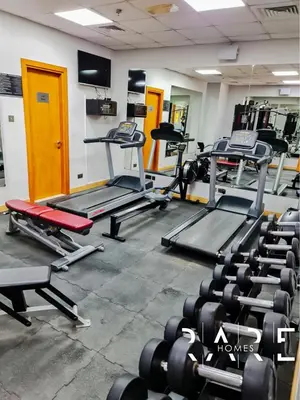 a gym with several treadmills and weights at Rare Holiday Homes - Near Miracle Garden - Lavender 2 - RG012 - Jumeirah Village Circle in Dubai