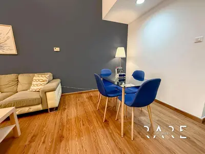 a living room with a couch and a table and chairs at Rare Holiday Homes - Near Miracle Garden - Lavender 2 - RG012 - Jumeirah Village Circle in Dubai