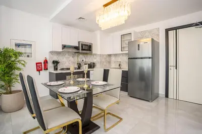 a kitchen with a dining table and a refrigerator at Homesgetaway -Spacious 1BR Apt in Pearlz by Danube in Dubai