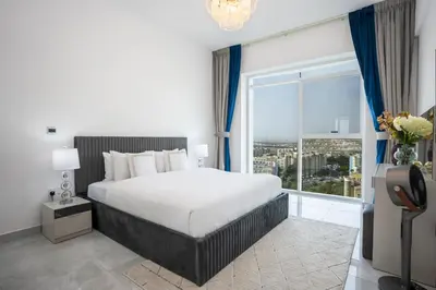 a bedroom with a large bed and a large window at Homesgetaway -Spacious 1BR Apt in Pearlz by Danube in Dubai