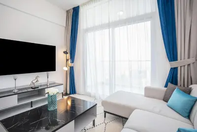 a living room with a couch and a large window at Homesgetaway -Spacious 1BR Apt in Pearlz by Danube in Dubai