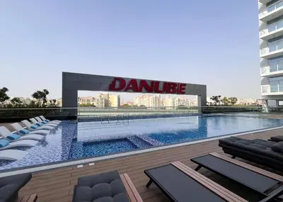 a swimming pool with lounge chairs in front of a building at Homesgetaway -Spacious 1BR Apt in Pearlz by Danube in Dubai