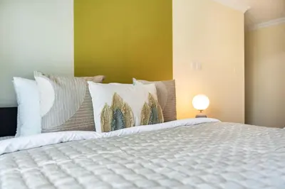 a bedroom with a white bed with a yellow wall at The Smart Concierge - Time Place in Dubai