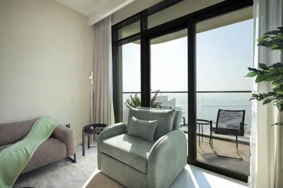 a living room with a chair and a large window at Stunning Palm View 1BR Apartment in Dubai Harbour in Dubai